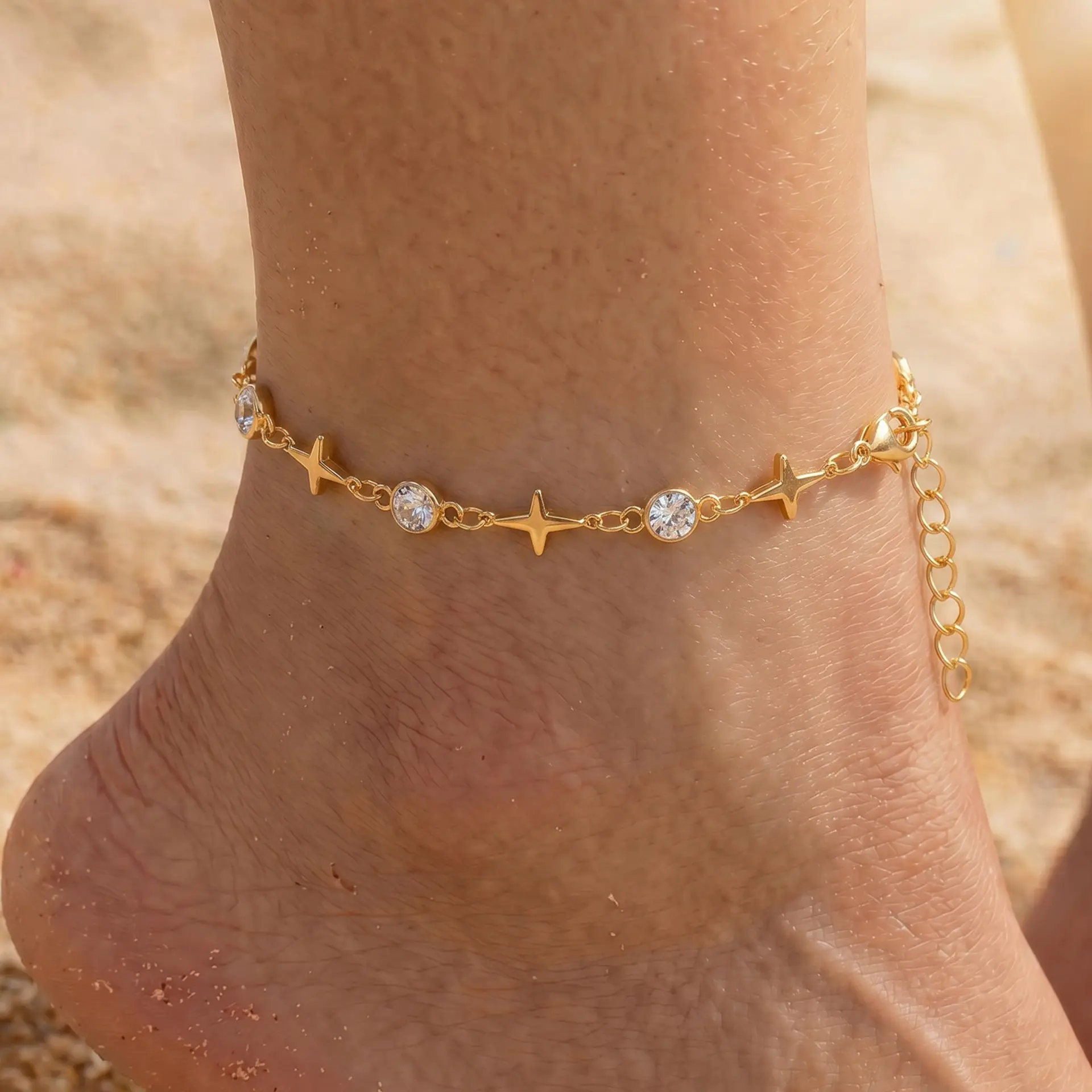 Popular minimalist European style ankle bracelet made of anti-tarnish electroplated alloy, decorated with geometric four-point star charms and round clear rhinestones in staggered layout. Equipped with extended adjustable tail chain to fit all ankle sizes, available in gold and silver two classic metallic tones. Ultra-slim lightweight chain design perfect for stackable matching, individually packed, ideal seaside travel souvenir foot accessory for women’s beach, daily and holiday styling.